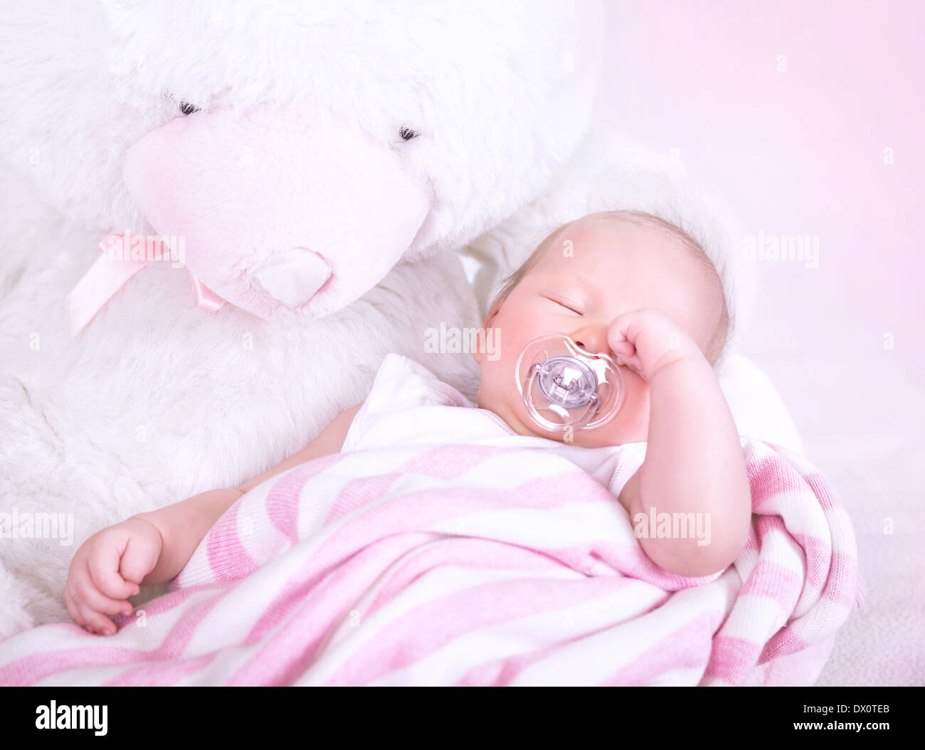 Cute newborn baby sleeping with pacifier in mouth, lying down on big