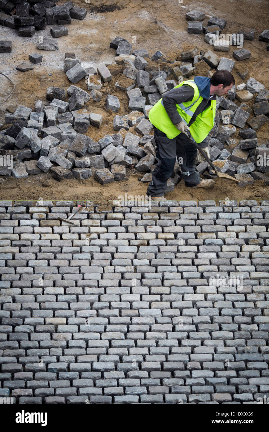 A workman at MOSI in Manchester, England UK restores the cobbled road inside the museum Stock Photo