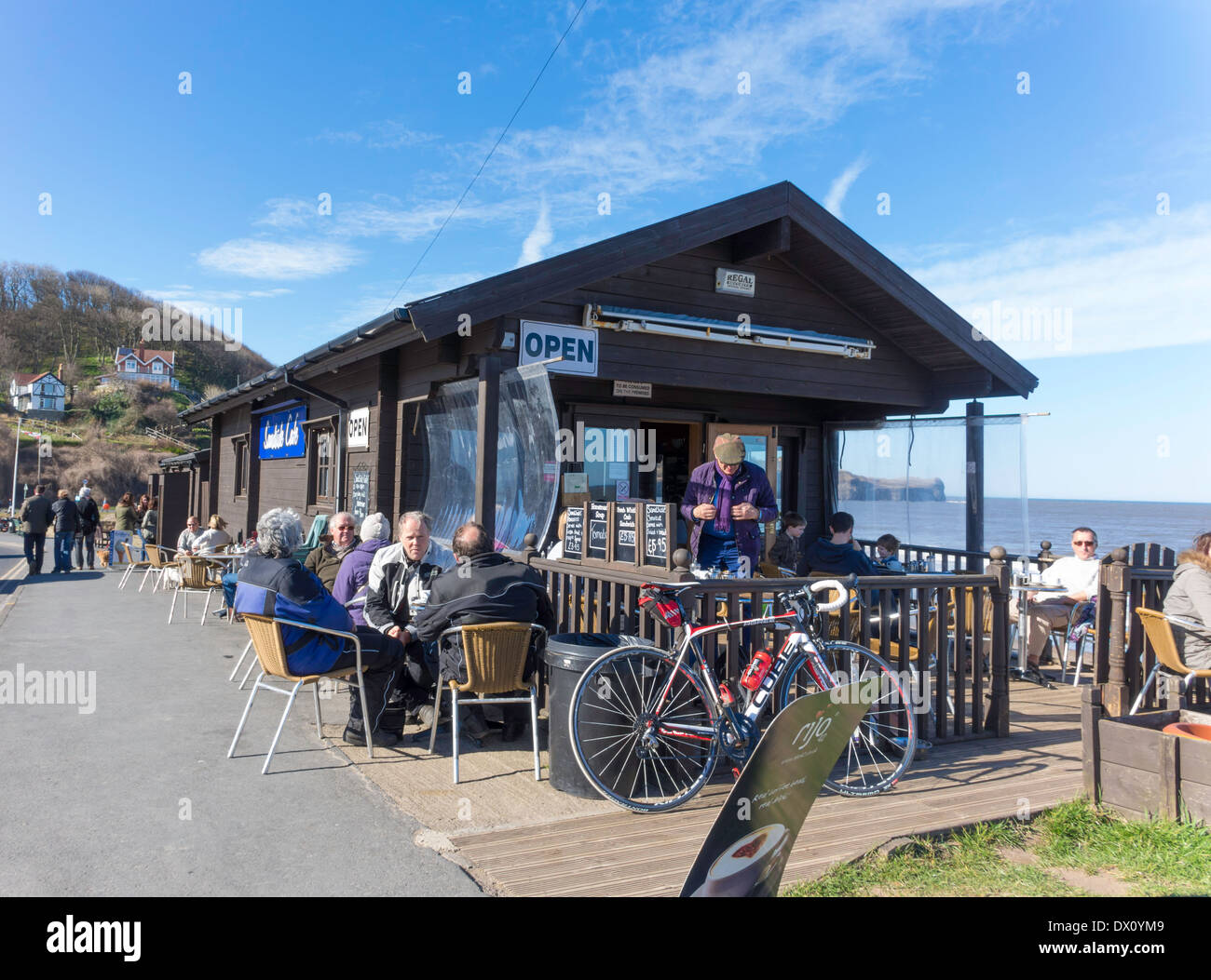Holiday makers at the Sandside café at Sandsend near Whitby North Yorkshire on a sunny but chilly spring day Stock Photo