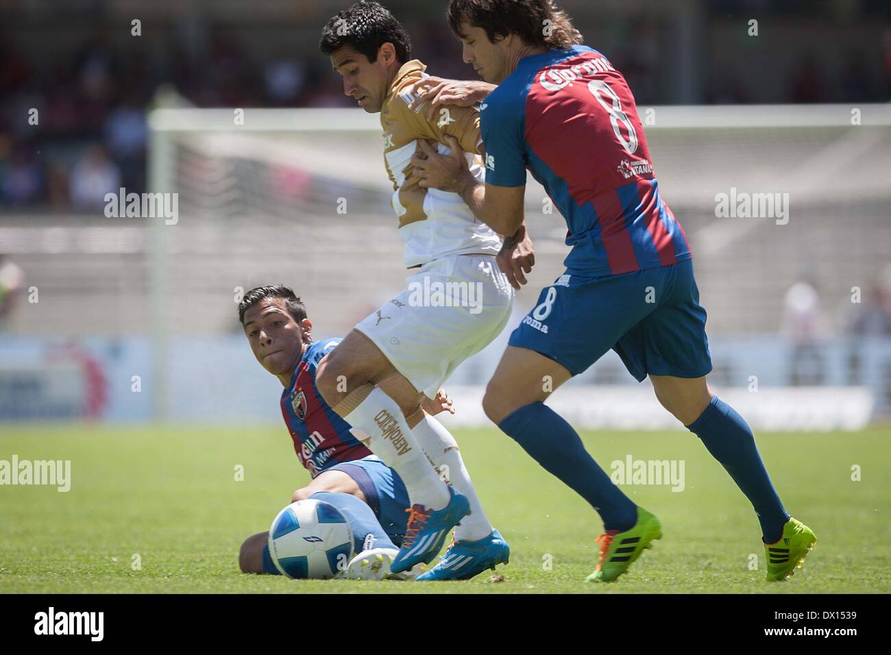 Mexico City, Mexico. 16th Mar, 2014. Luis Fuentes(C) of UNAM's Pumas vies for the ball with Martin Galmarini(R) of Atlante during their match of the 2014 MX League Closing Tournament at University Olympic Stadium in Mexico City, capital of Mexico, on March 16, 2014. Credit:  Pedro Mera/Xinhua/Alamy Live News Stock Photo
