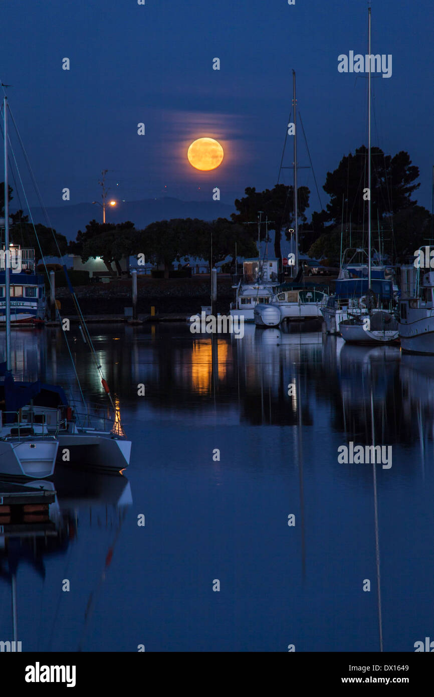 The setting Worm Full Moon reflected in the San Leandro Marina. Stock Photo