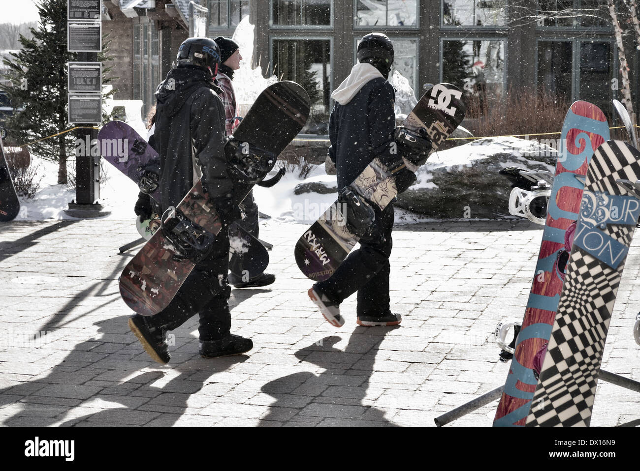Snowboarders walking trough Stowe Vermont ski resort New England USA Stock Photo