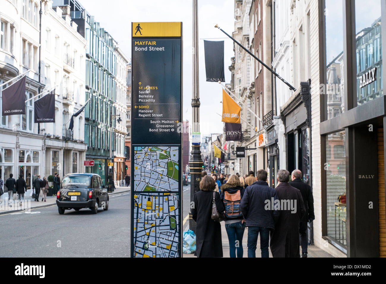 LONDON, UK - MARCH 14: Direction signs post in Mayfair, with famous shop banners and pedestrians passing by in the background. Stock Photo