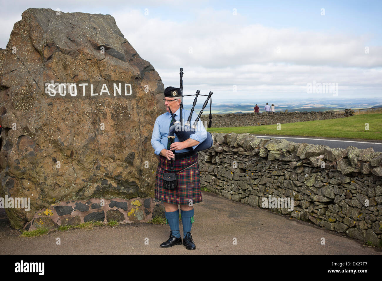 A man playing his bagpipes entertaining visitors to the border crossing