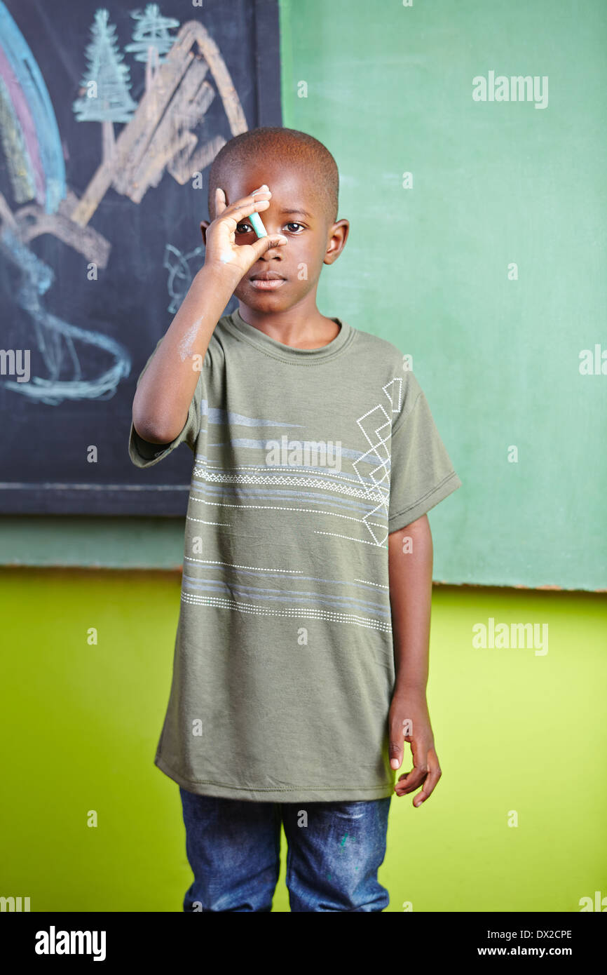 African boy standing with chalk in front of blockboard in a kindergarten  Stock Photo - Alamy