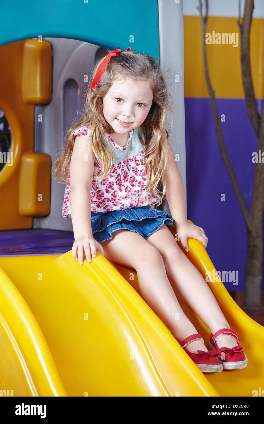 Happy girl playing on a slide in a kindergarten Stock Photo