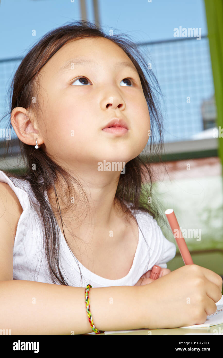 Asian girl drawing in kindergarten with pen on paper Stock Photo