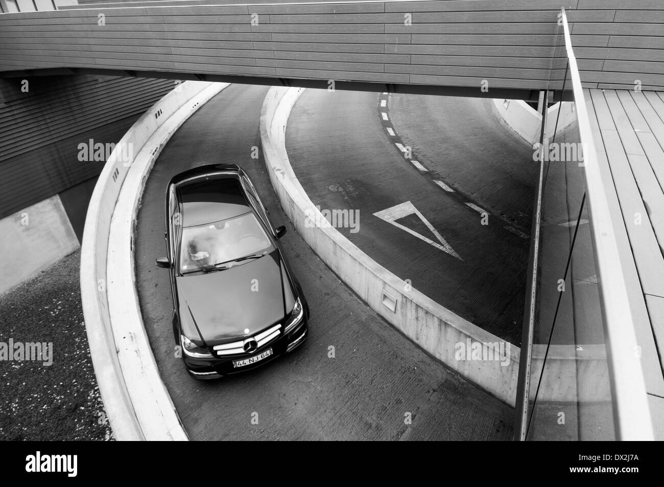 car driving down a ramp into an underground car park Stock Photo