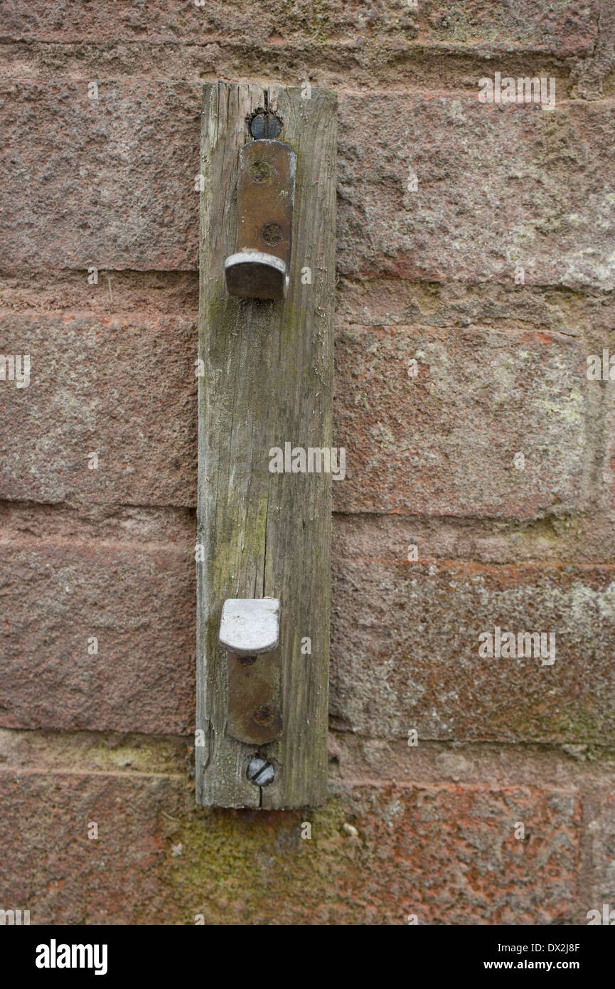 Metal cleat for washing line on wooden bracket attached to brick wall Stock Photo