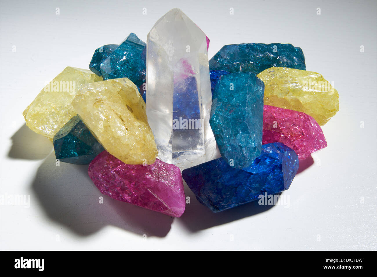 Pieces of artificially colored crystal with a clear quartz  crystal in the middle Stock Photo