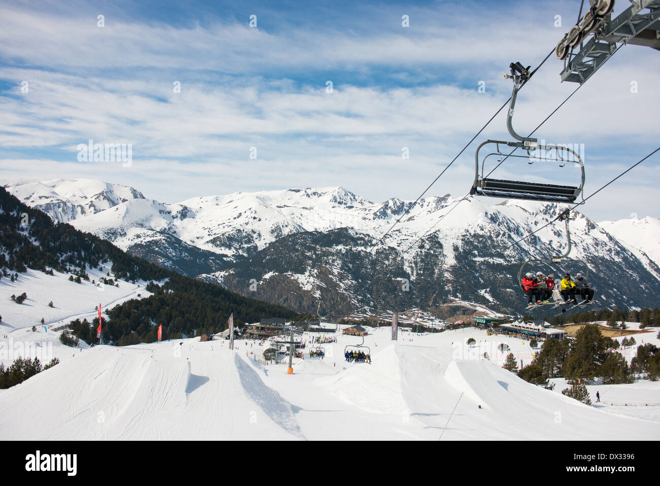 Chair lifts in Soldeu, Andorra winter sports resort. Skiers sitting on a chair lift hovering over the slope style free ski area of Soldeu in the sun. Stock Photo
