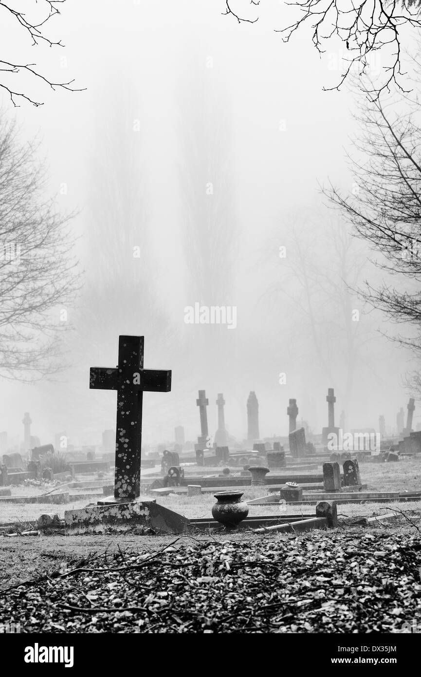 Cross Gravestone in the fog at Banbury Cemetery, Oxfordshire, England. Monochrome Stock Photo