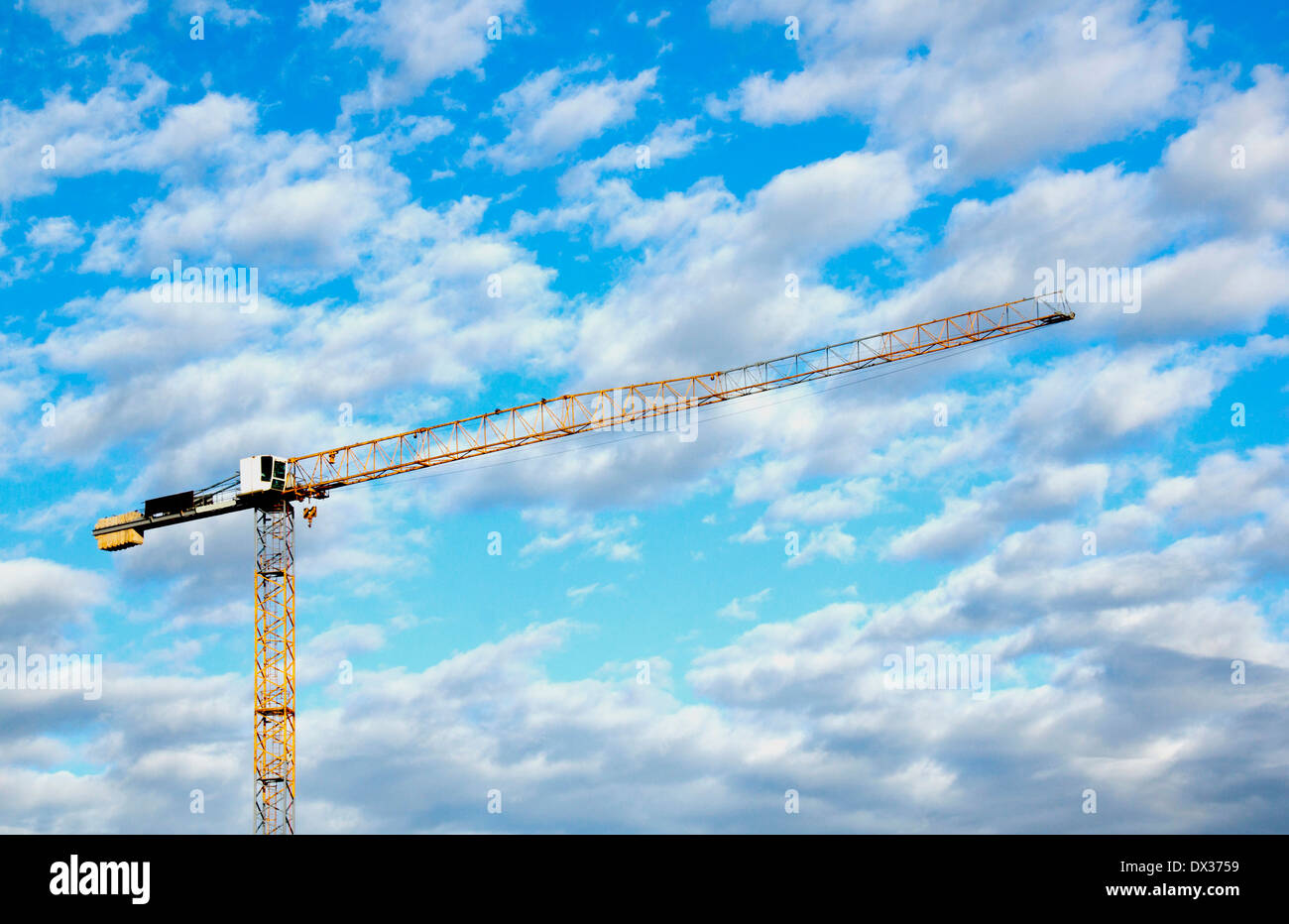 Tall yellow tower crane against blue cloudy sky Stock Photo - Alamy
