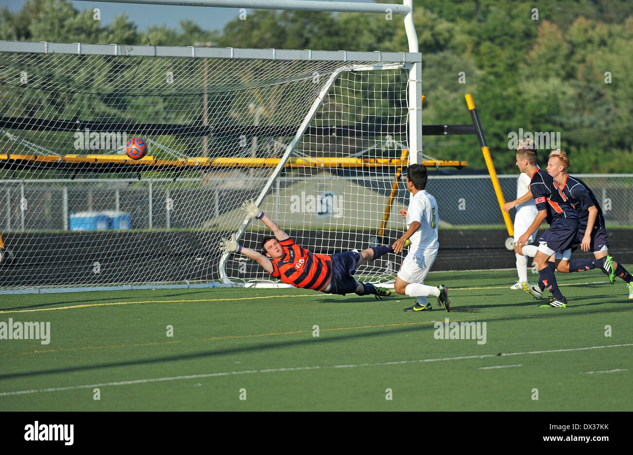 Soccer/football  player slams a rebound past a diving goal keeper for a score during a high school match. USA. Stock Photo