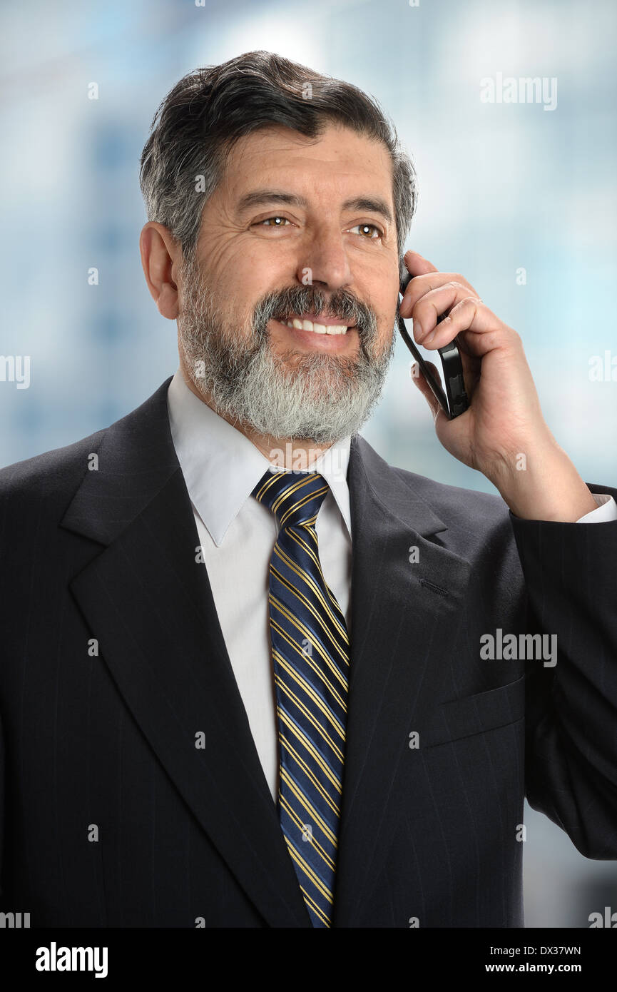 Portrait of senior Hispanic businessman using cell phone inside office Stock Photo