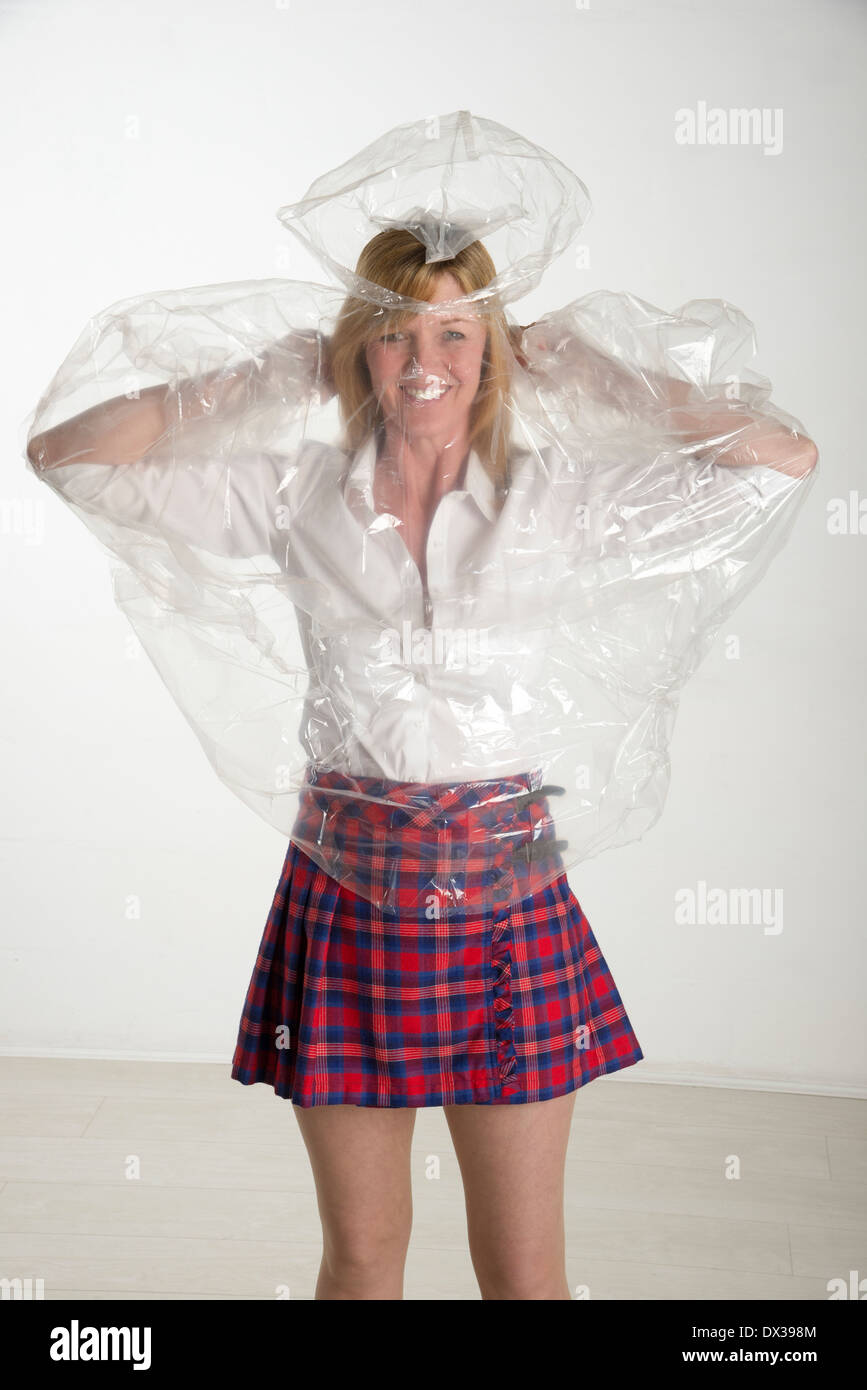 Woman putting on a plastic see through poncho mac Stock Photo