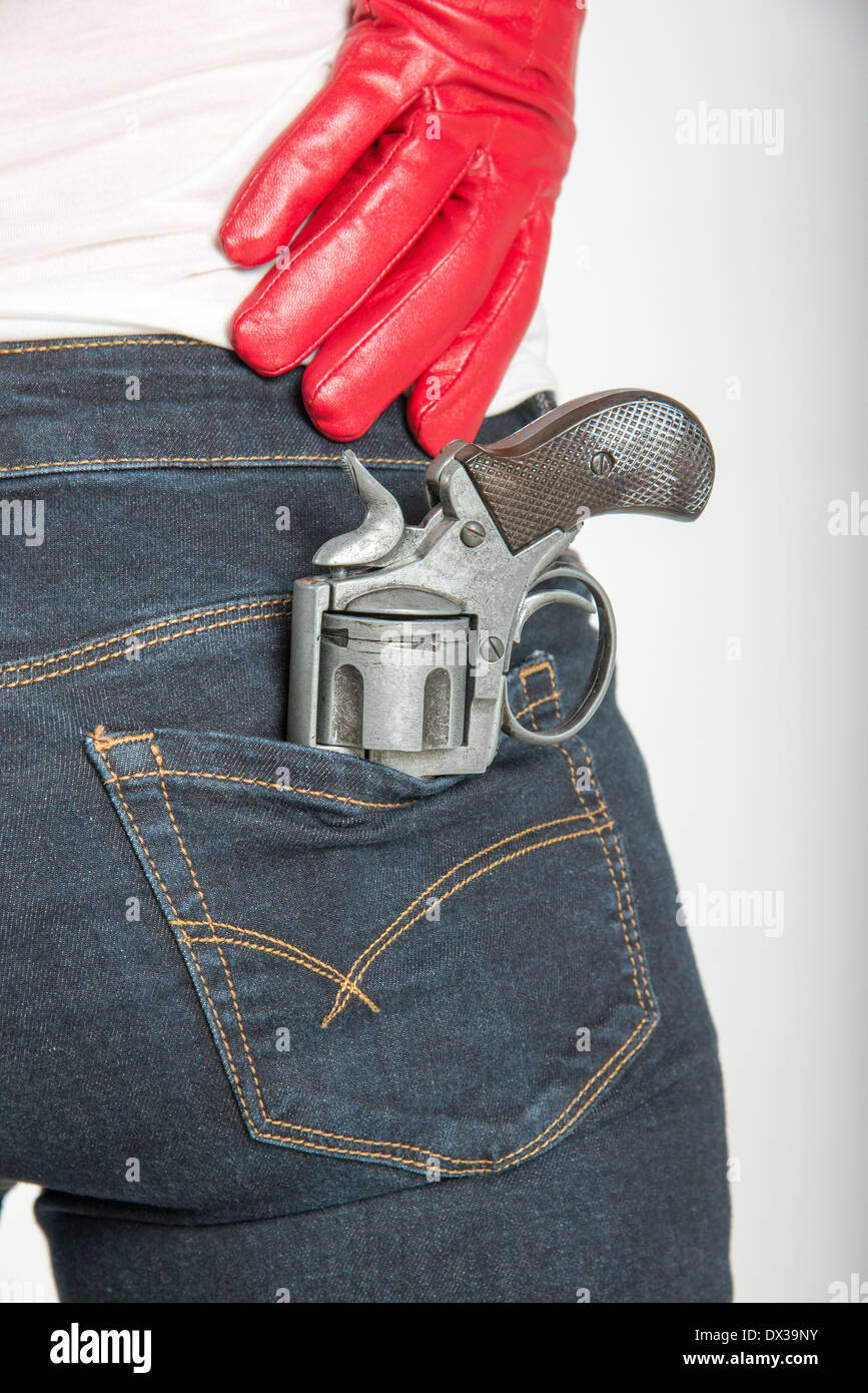 Woman wearing red leather glove holding a gun. Keeping a revolver in her waistband Stock Photo
