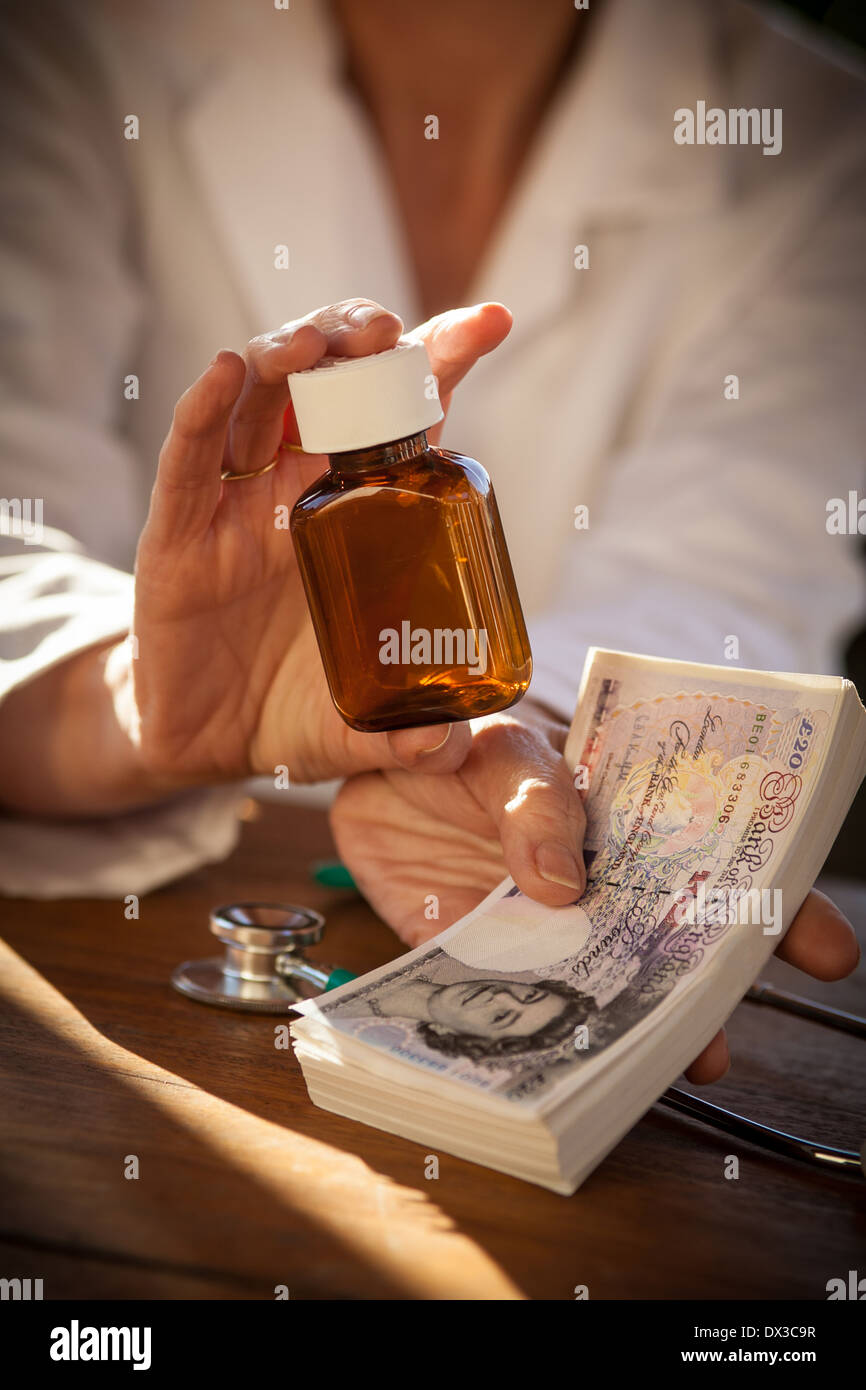 Close up of a Female doctor holding a medicine bottle and a wad of money Stock Photo