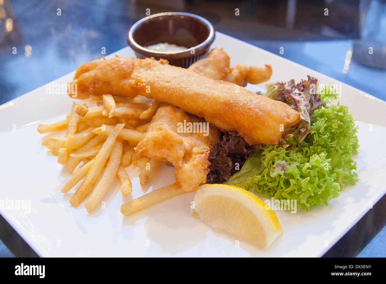 Fish and Chips Over Lettuce Salad Lemon Wedge with Tartar Sauce Closeup Stock Photo