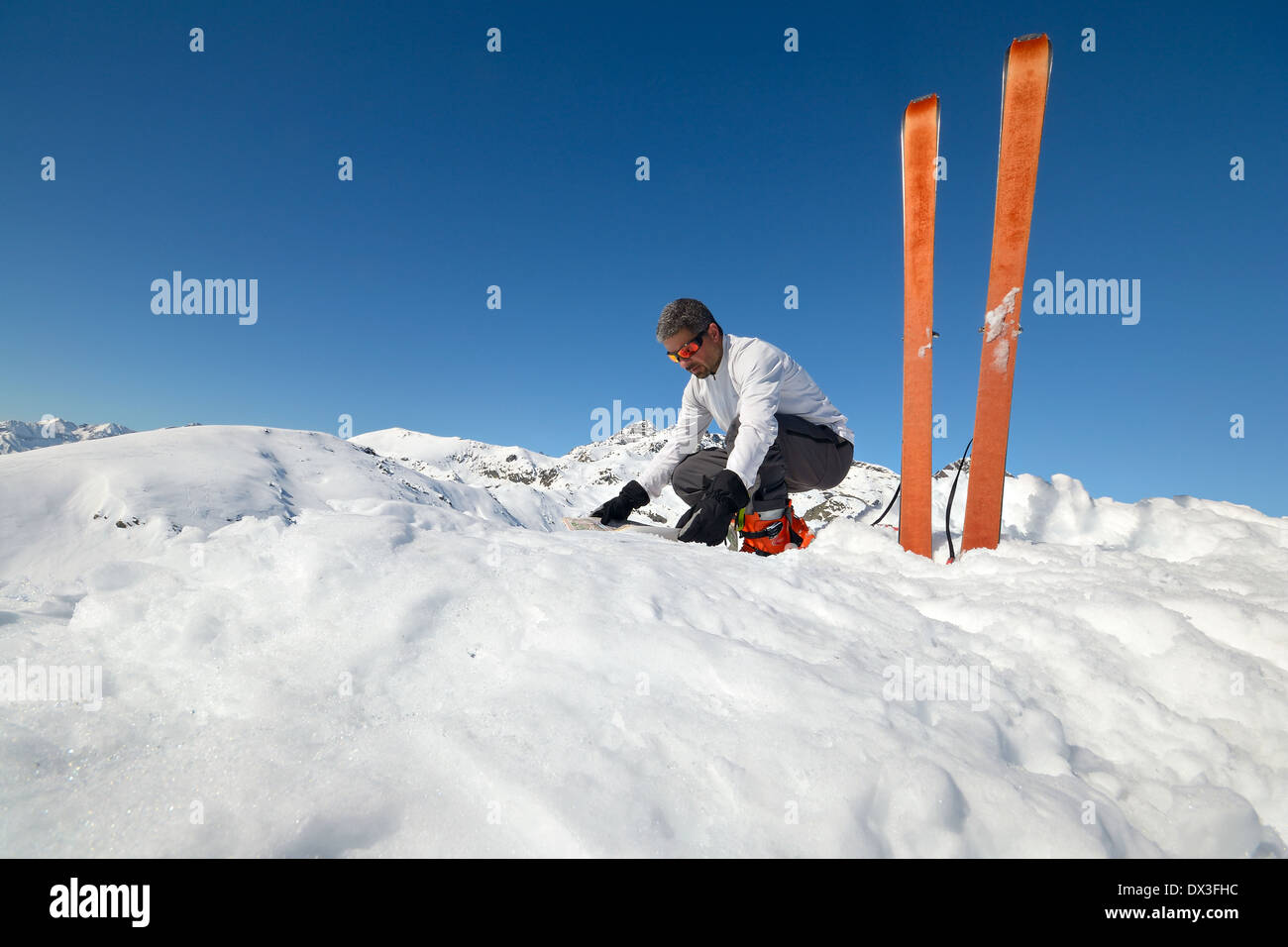 Alpinist watching a map on the summit. Pair of back country ski with sealskin. Stock Photo
