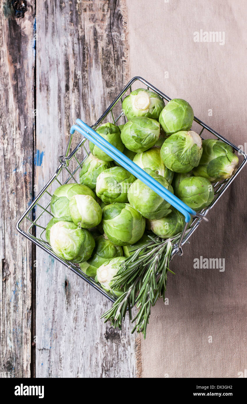 Top view on food basket of brussels sprouts and rosemary on old wooden table. Stock Photo