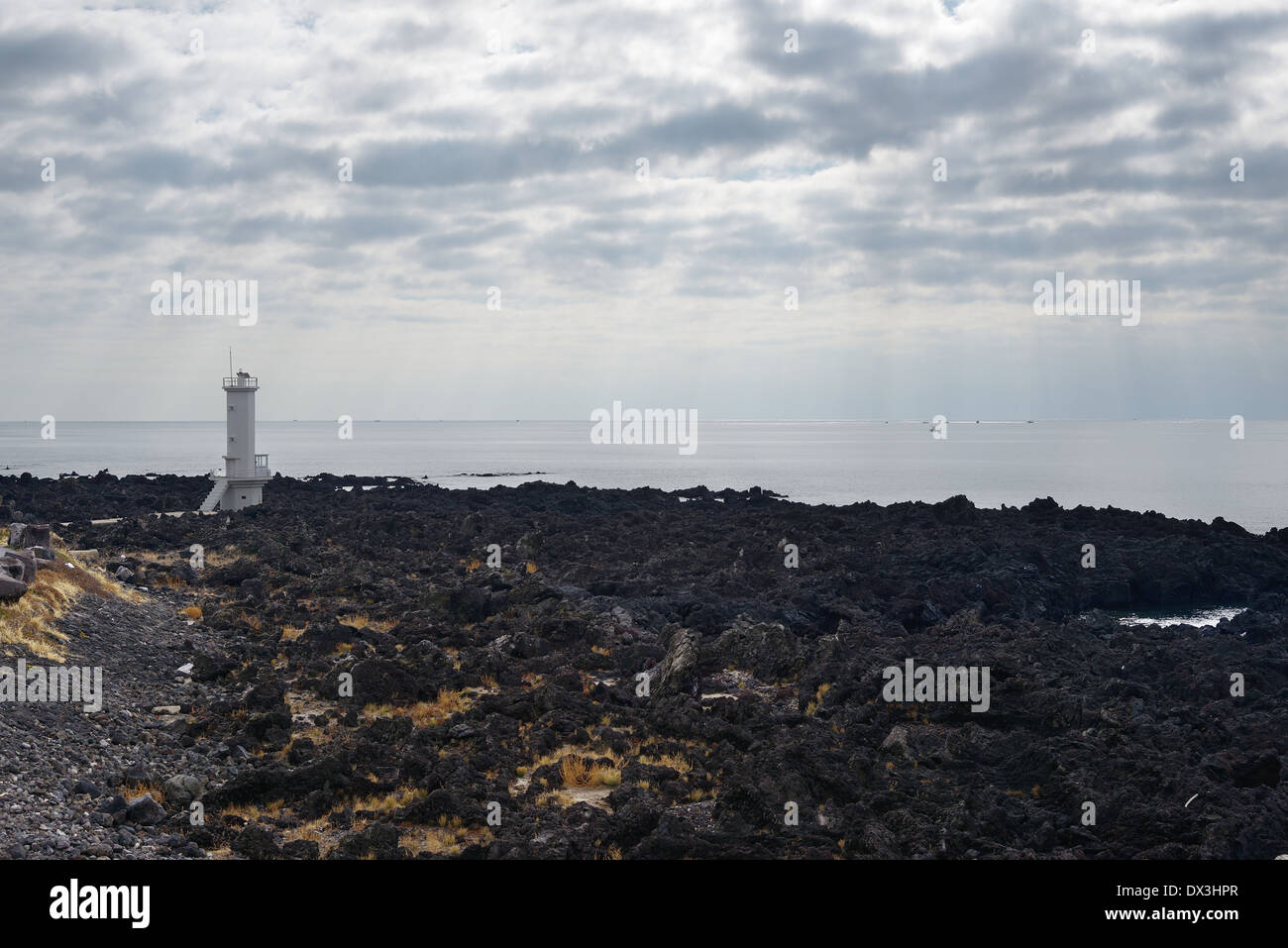 White Light House in basaltic seaside in Jeju Island Stock Photo