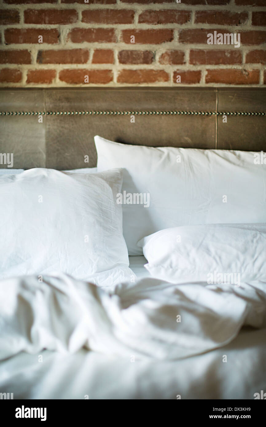 White bedding on unmade bed in bedroom Stock Photo