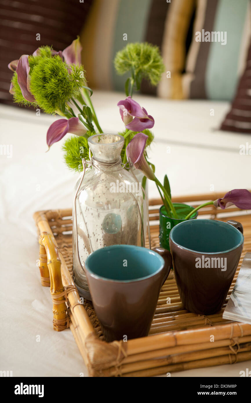 Flowers in vase and mugs on bamboo tray on bed, close up, high angle view Stock Photo