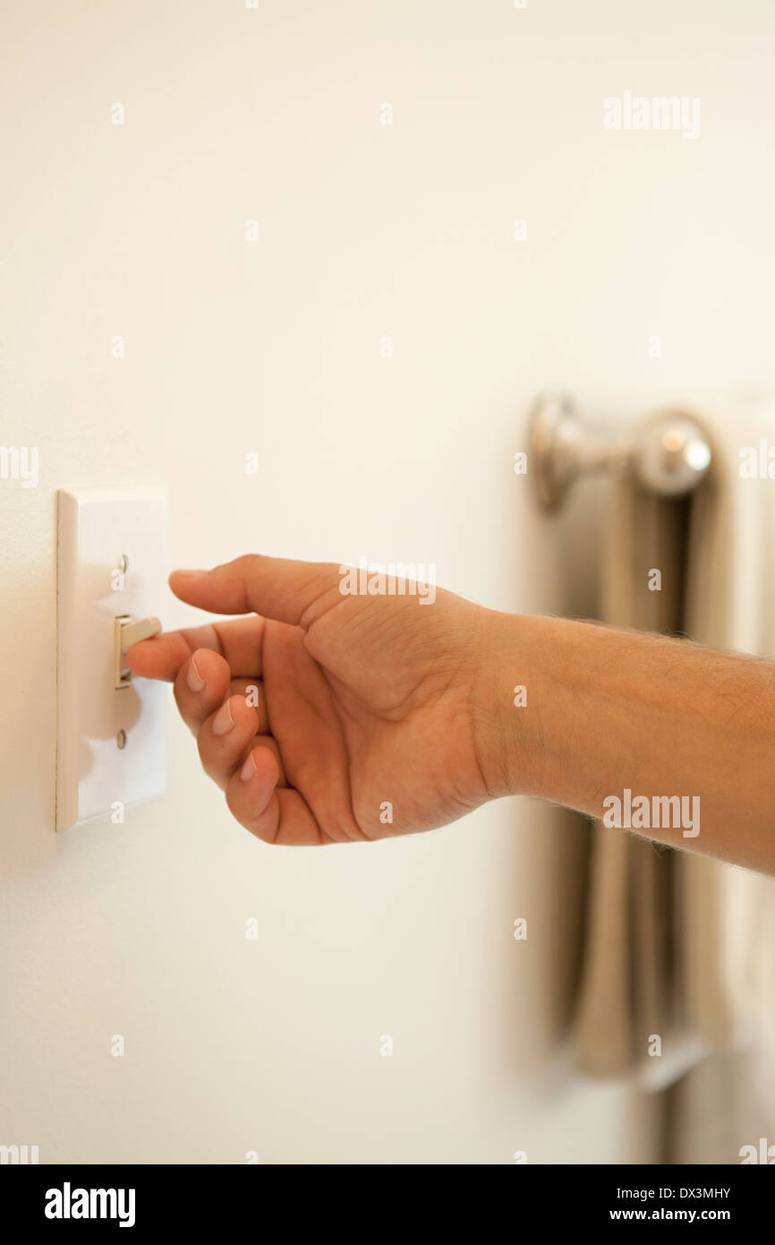 Man's hand turning on light switch, close up Stock Photo