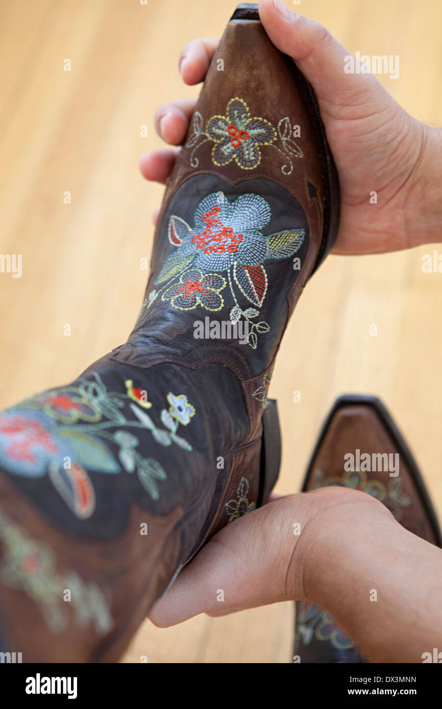 Floral cowboy boots, man putting on woman's foot, close up, high angle view Stock Photo