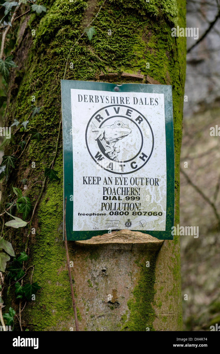 Sign posted on tree warning of poachers on river Derbyshire England Stock Photo