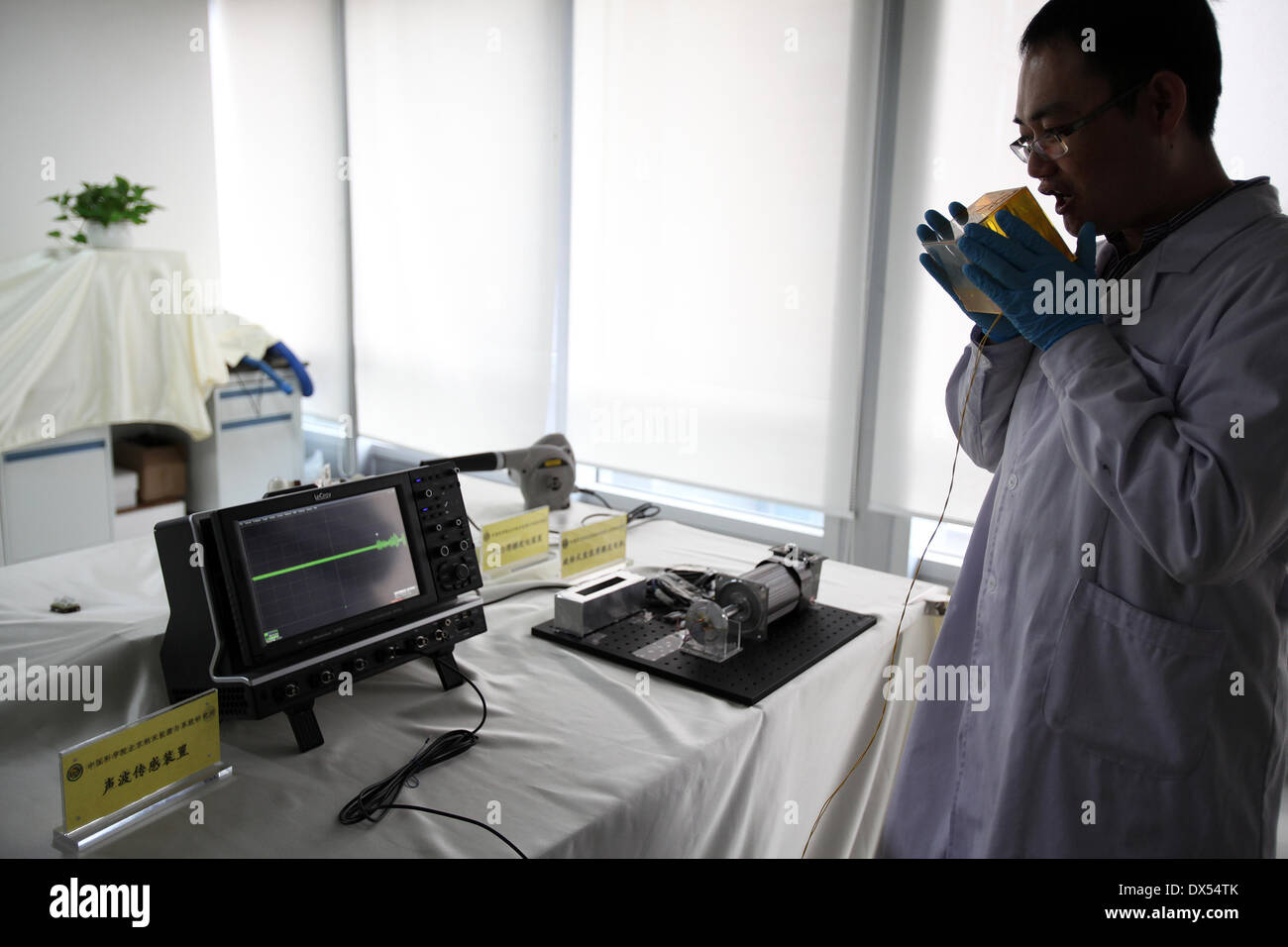 Beijing, China. 18th Mar, 2014. A scientist speaks to a device capturing acoustic waves and coverting them into electric signals during a demonstration on triboelectric generation at the Beijing Institute of Nanoenergy and Nanosystems under Chinese Academy of Sciences, Beijing, China, March 18, 2014. The institute showed their latest research results on triboelectric generators here on Tuesday. This technology could convert random mechanical energy from our environment into electric energy. Credit:  Jin Liwang/Xinhua/Alamy Live News Stock Photo