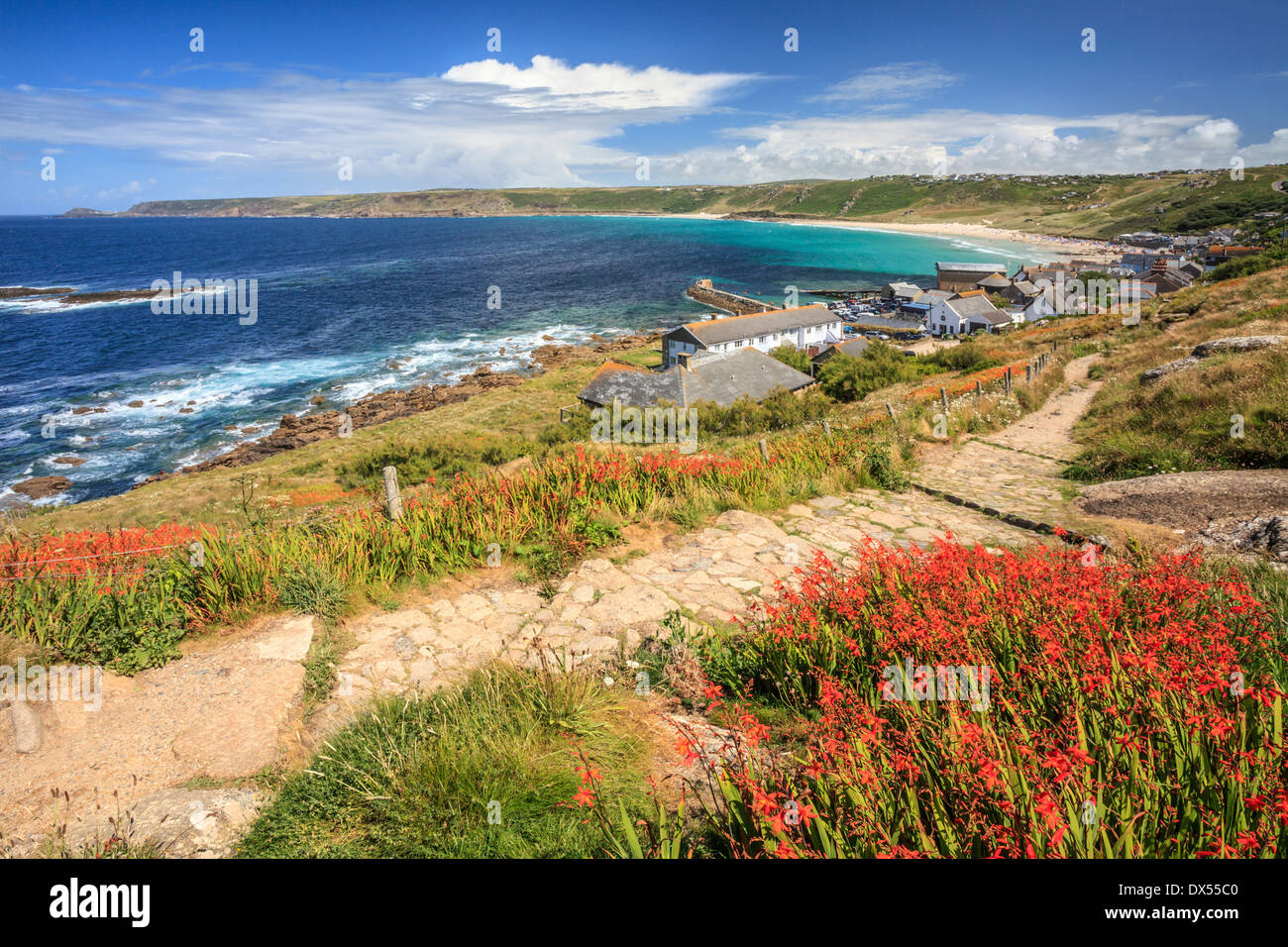 Sennen Cove in Cornwall with a display a Montbretia in the foreground Stock Photo