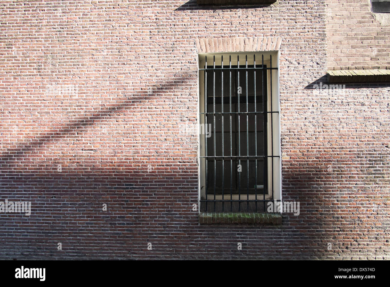 warehouse window with metal security bars in shadow light amsterdam