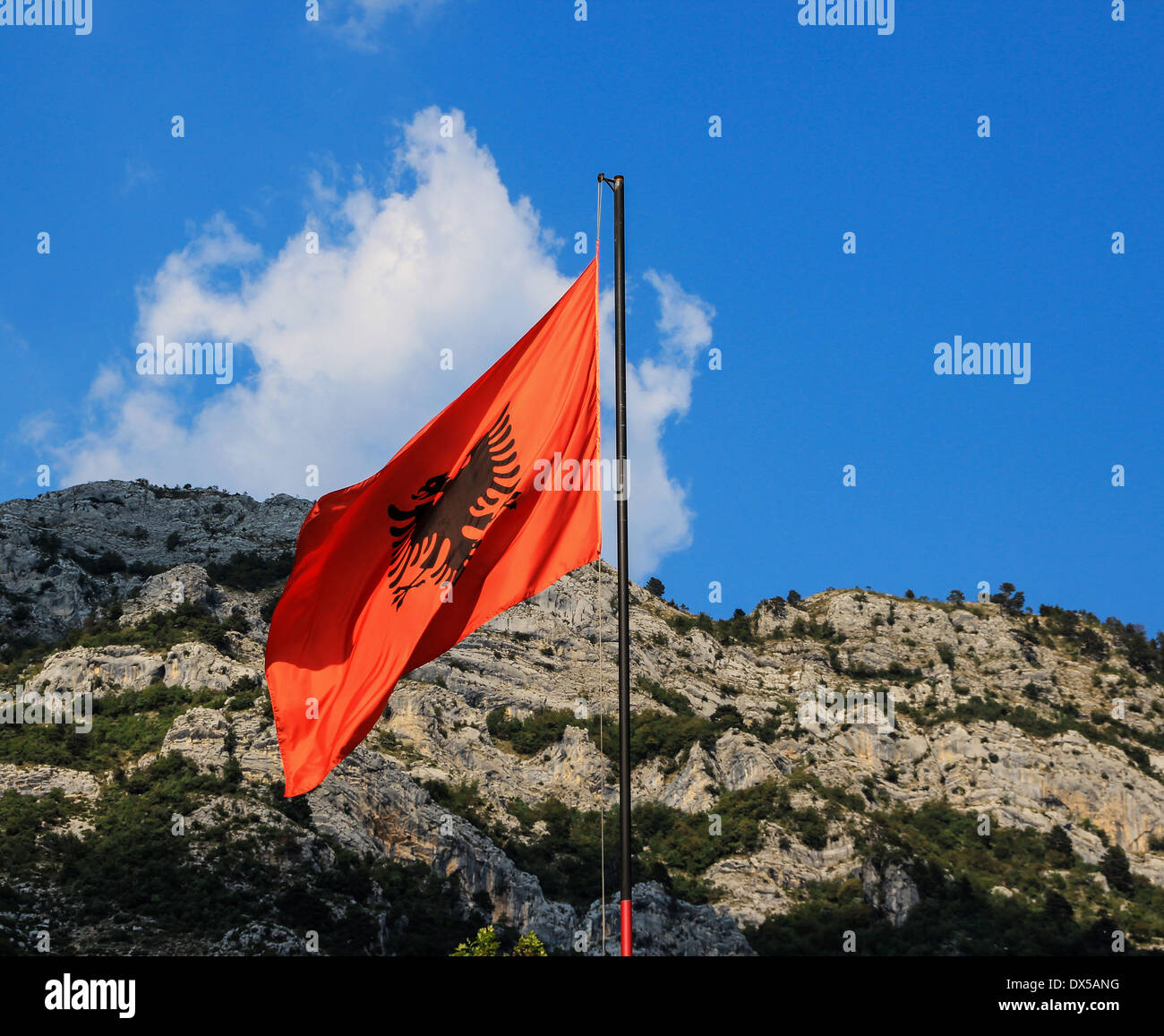 Albanian flag with black eagle on red background, with background the mountains around Kruja Castle, the Castle of national hero Skanderbeg Stock Photo