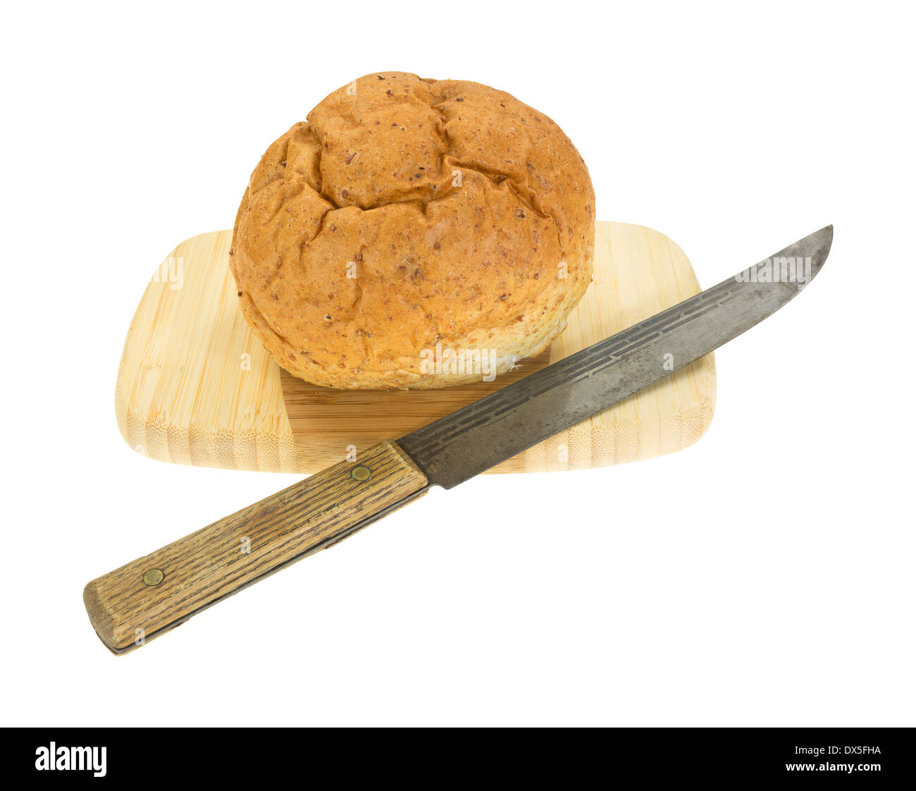 A small whole wheat boule bread on a wood cutting board with old kitchen knife. Stock Photo