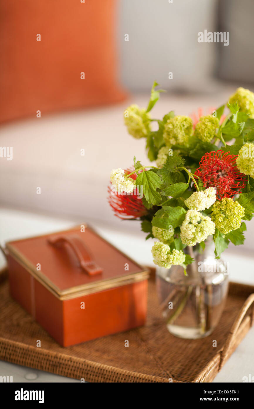Spider mums and green and white viburnum flower bouquet in vase on tray with leather box Stock Photo