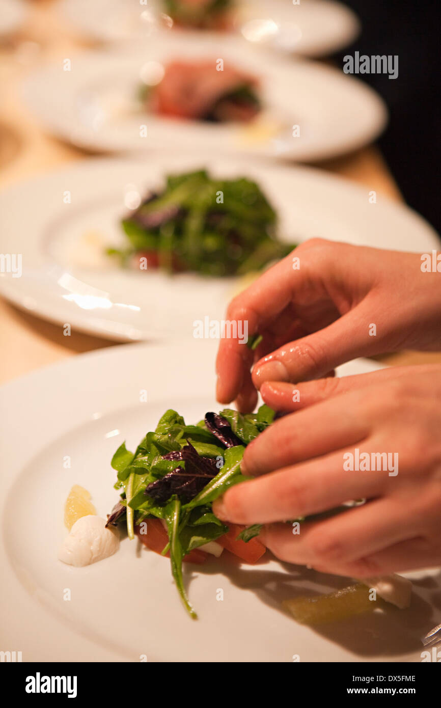 Woman plating salads in a row Stock Photo