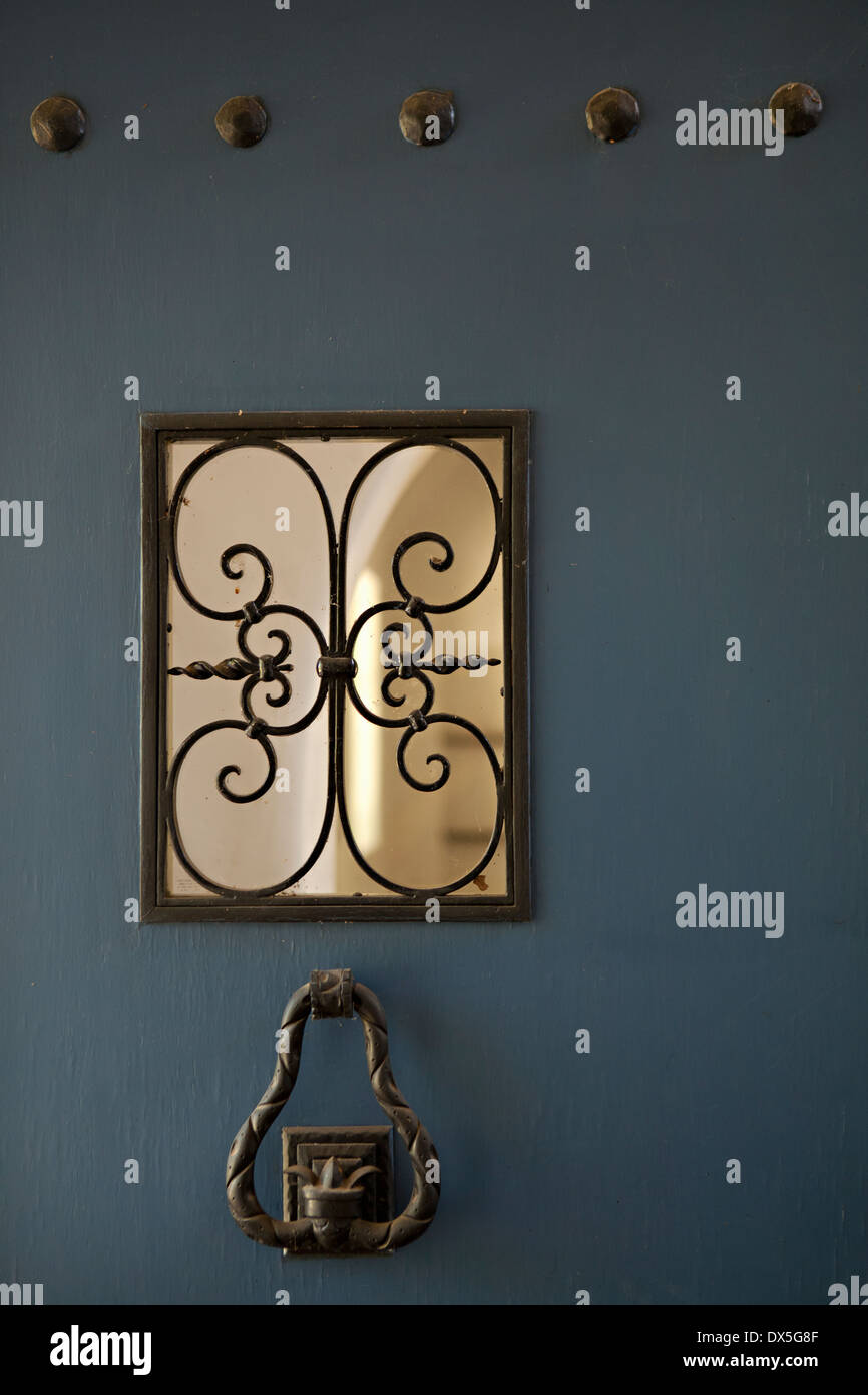 Iron door knocker and window detail on blue Spanish front door Stock Photo