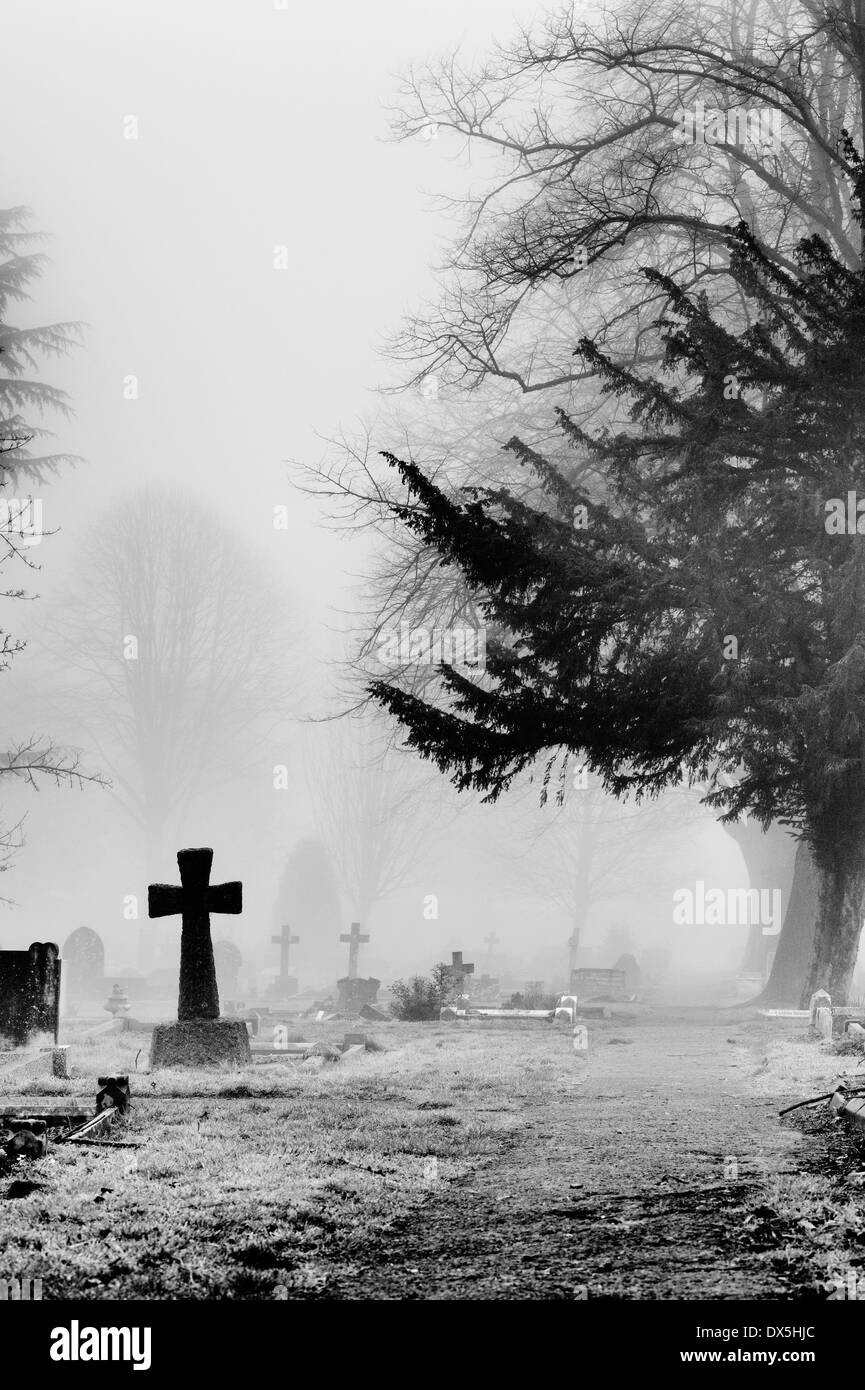 Cross Gravestone in the fog at Banbury Cemetery, Oxfordshire, England. Monochrome Stock Photo