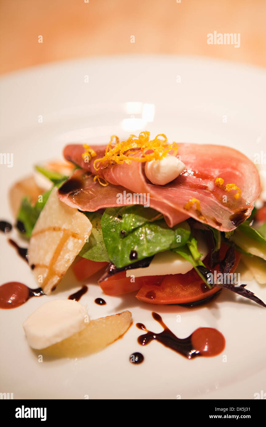 Composed salad with prosciutto, spinach, tomato, cheese and balsamic vinegar, close up Stock Photo