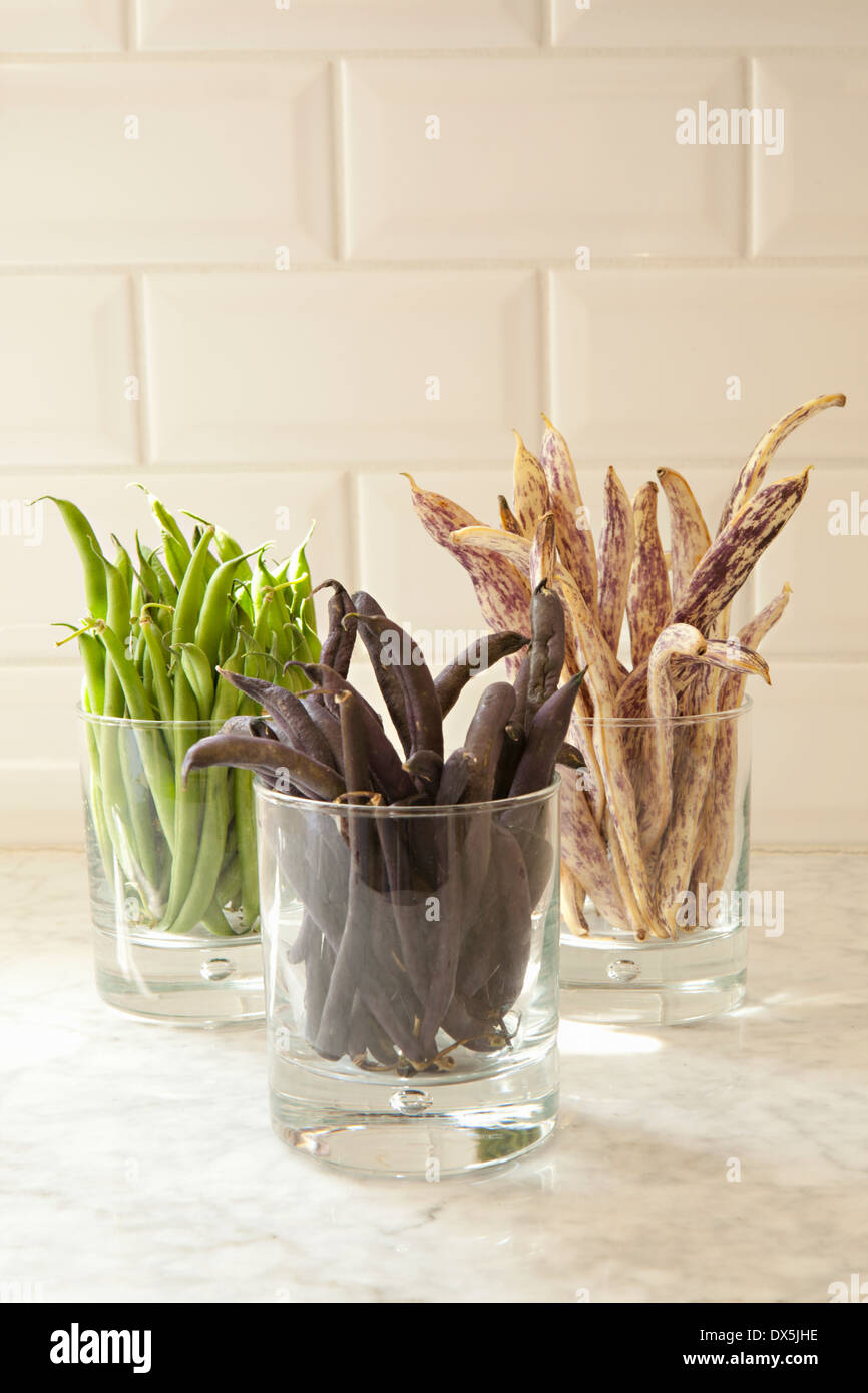 Variety of colorful beans in glasses on domestic kitchen counter, close up Stock Photo