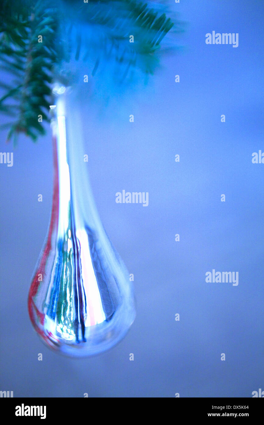 Icicle ornament hanging from Christmas tree branch on blue background, close up Stock Photo