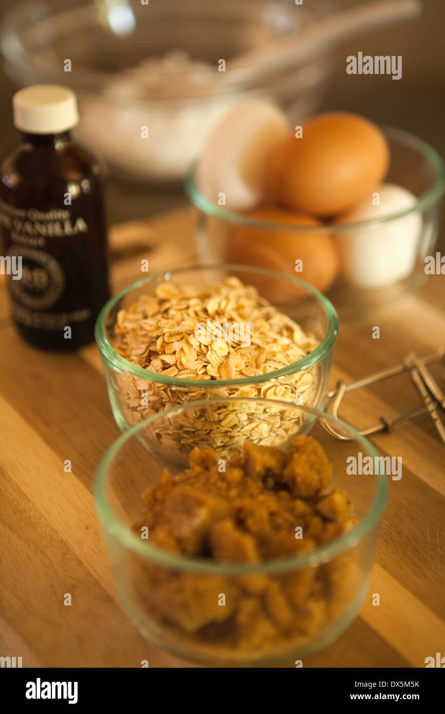 Cake baking ingredients in domestic kitchen, vanilla extract, brown sugar, oats, eggs, flour Stock Photo