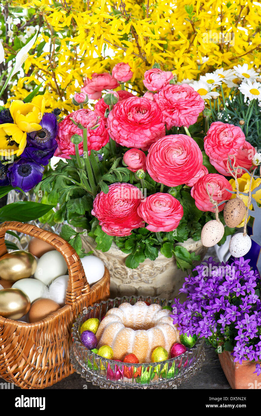 fresh spring flowers with easter cake and eggs decoration. ranunculus, campanula, forsythia, tulips, anemone Stock Photo