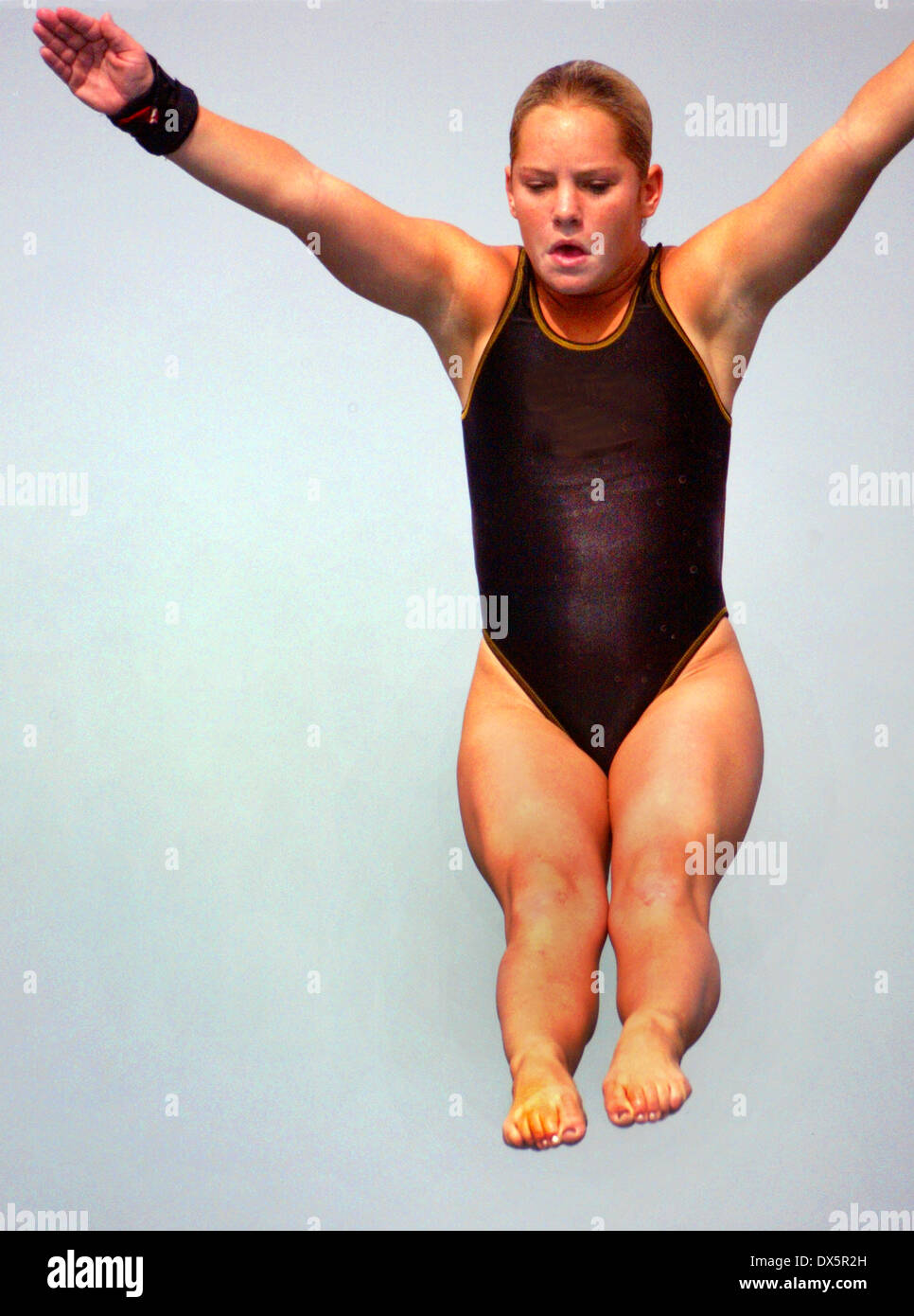 A woman competition diver jumps from a high diving board in Mission