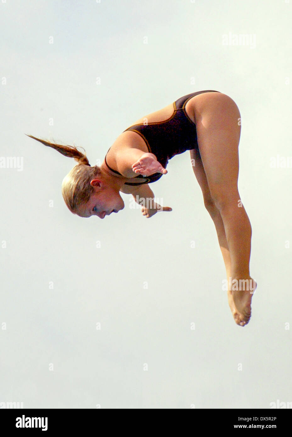 A woman competition diver jumps from a high diving board in Mission