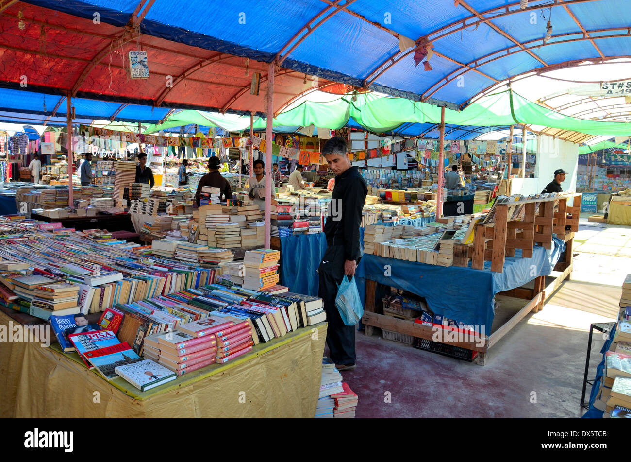 Man browses books at open air book stall in Sunday Bazaar Karachi