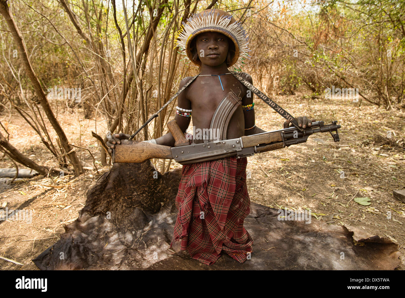 Mursi boy with Kalashnikov in the Lower Omo Valley of Ethiopia Stock Photo