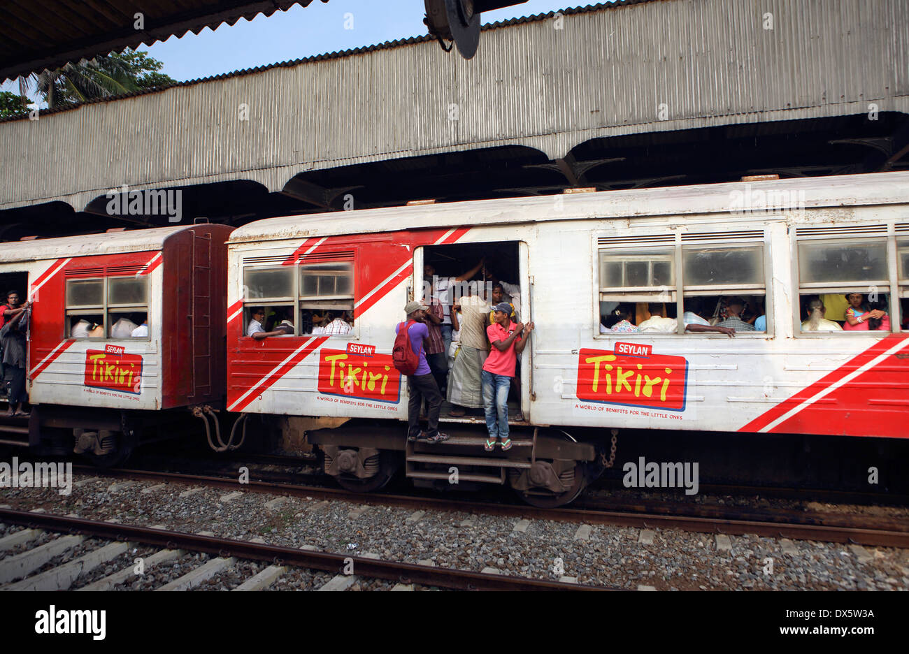 People hanging from open doors of commuter train passing through Mount
